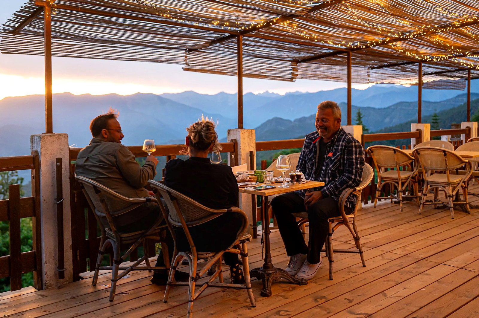 Convives sur la terrasse du Refuge au coucher du soleil, face aux montagnes